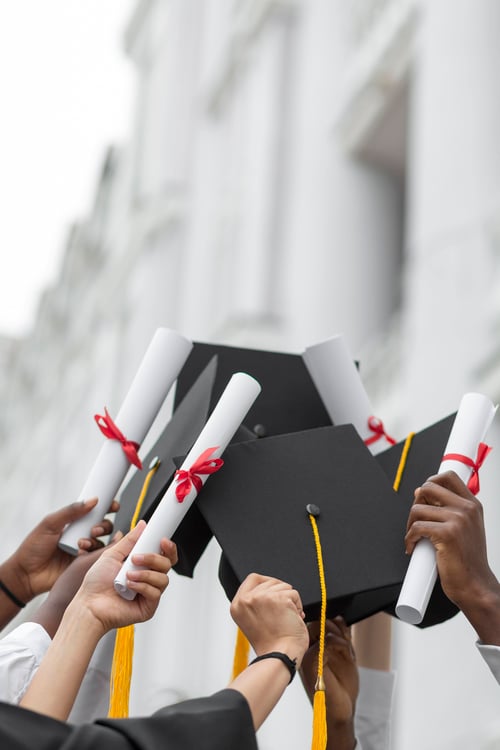 close-up-hands-holding-diplomas-caps